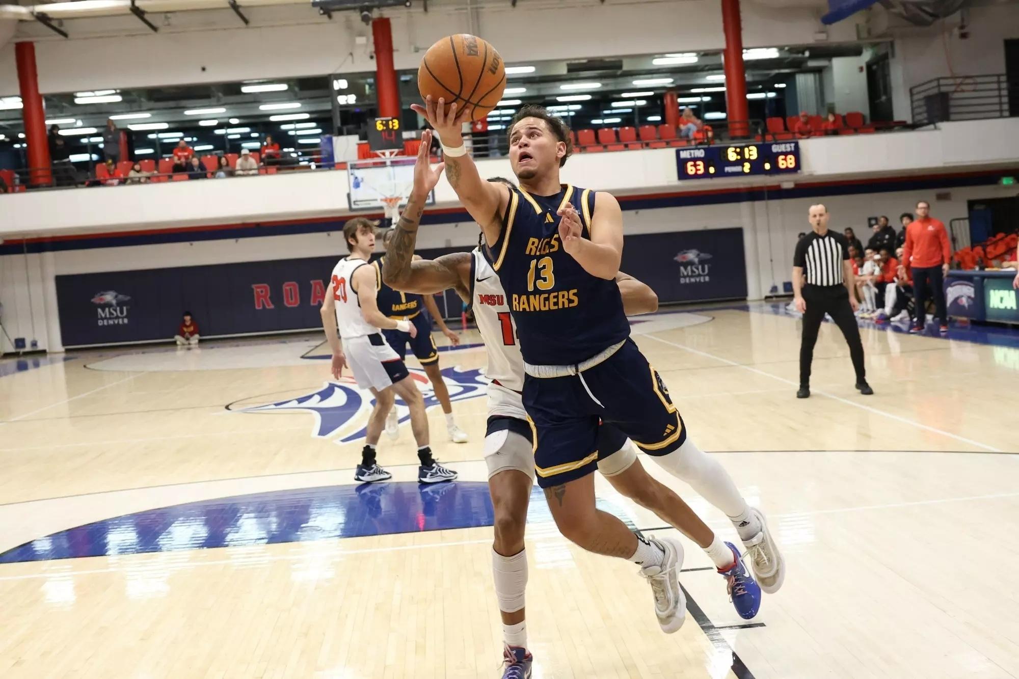 Regis' Kobe Sanders in his blue away jersey jumps to score a layup. 